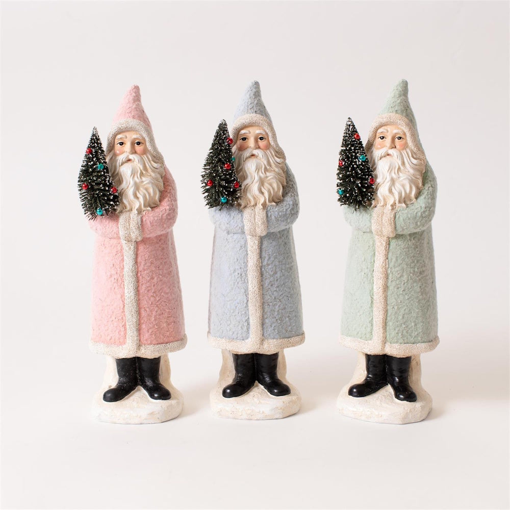 Three vintage Santa figurines in pastel pink, blue, and green robes holding small Christmas trees.