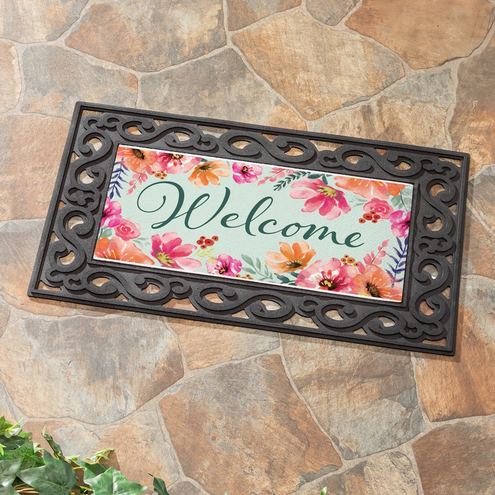 Pastels of Nature floral welcome mat with pink and orange flowers in a black scrollwork frame on a stone patio.