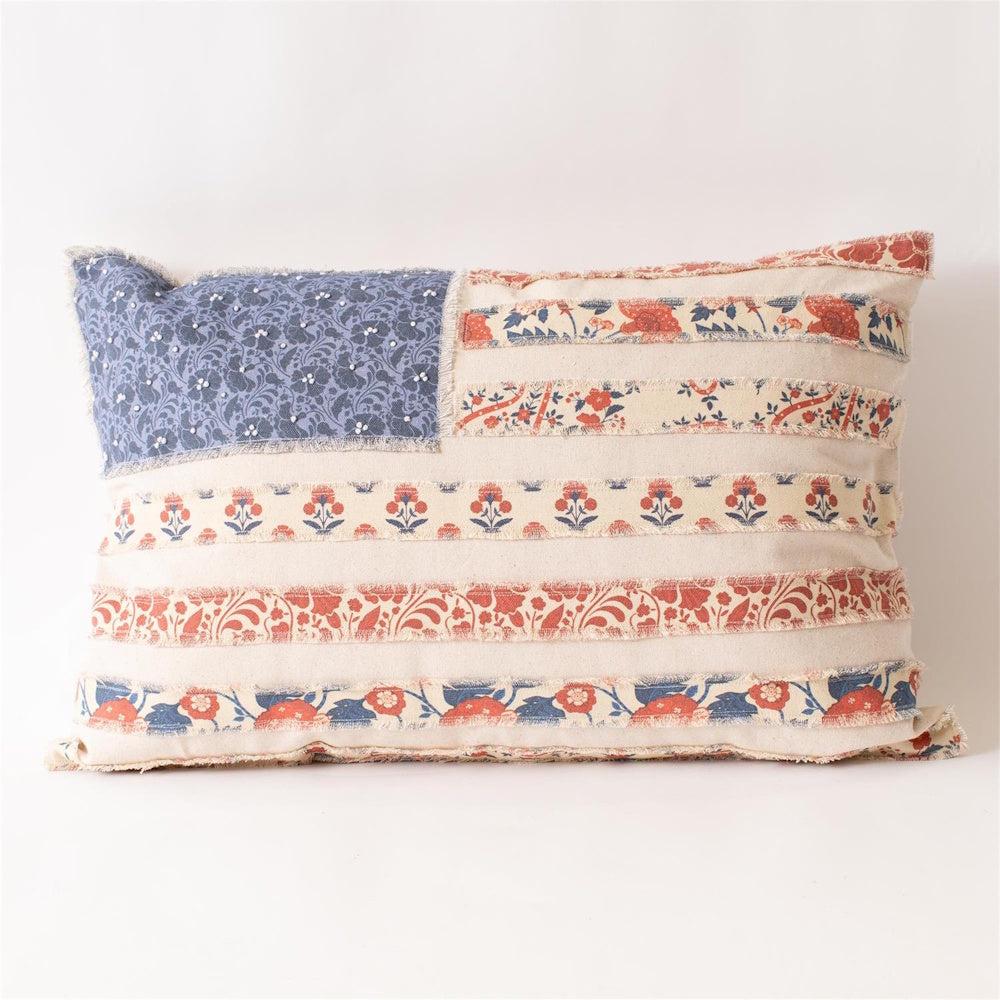 Patchwork lumbar pillow featuring a floral American flag design with red and blue patterned fabric stripes on cream canvas.