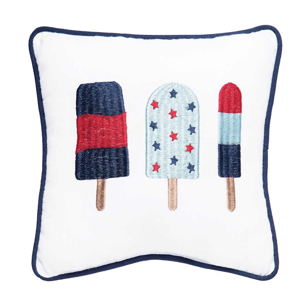 White throw pillow with navy trim featuring embroidered red, white, and blue popsicles in three different styles.
