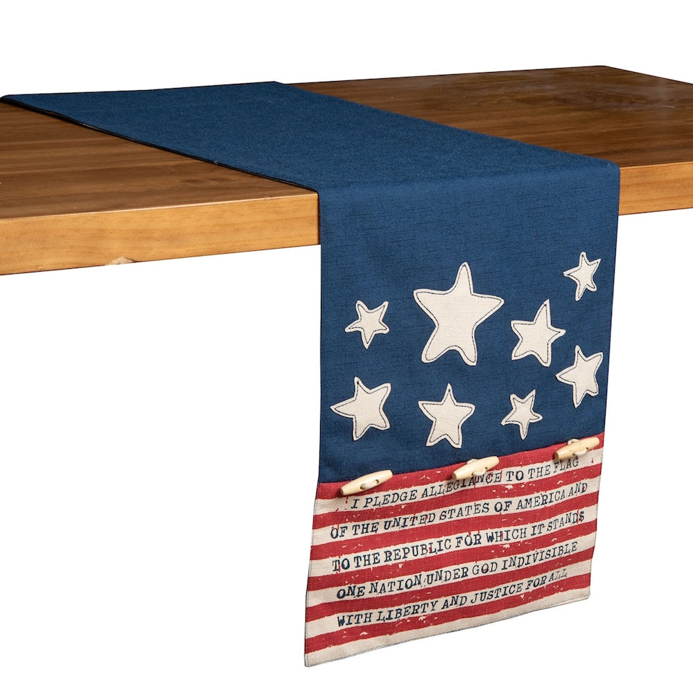Patriotic table runner with stars and stripes featuring the Pledge of Allegiance draped over a wooden table.