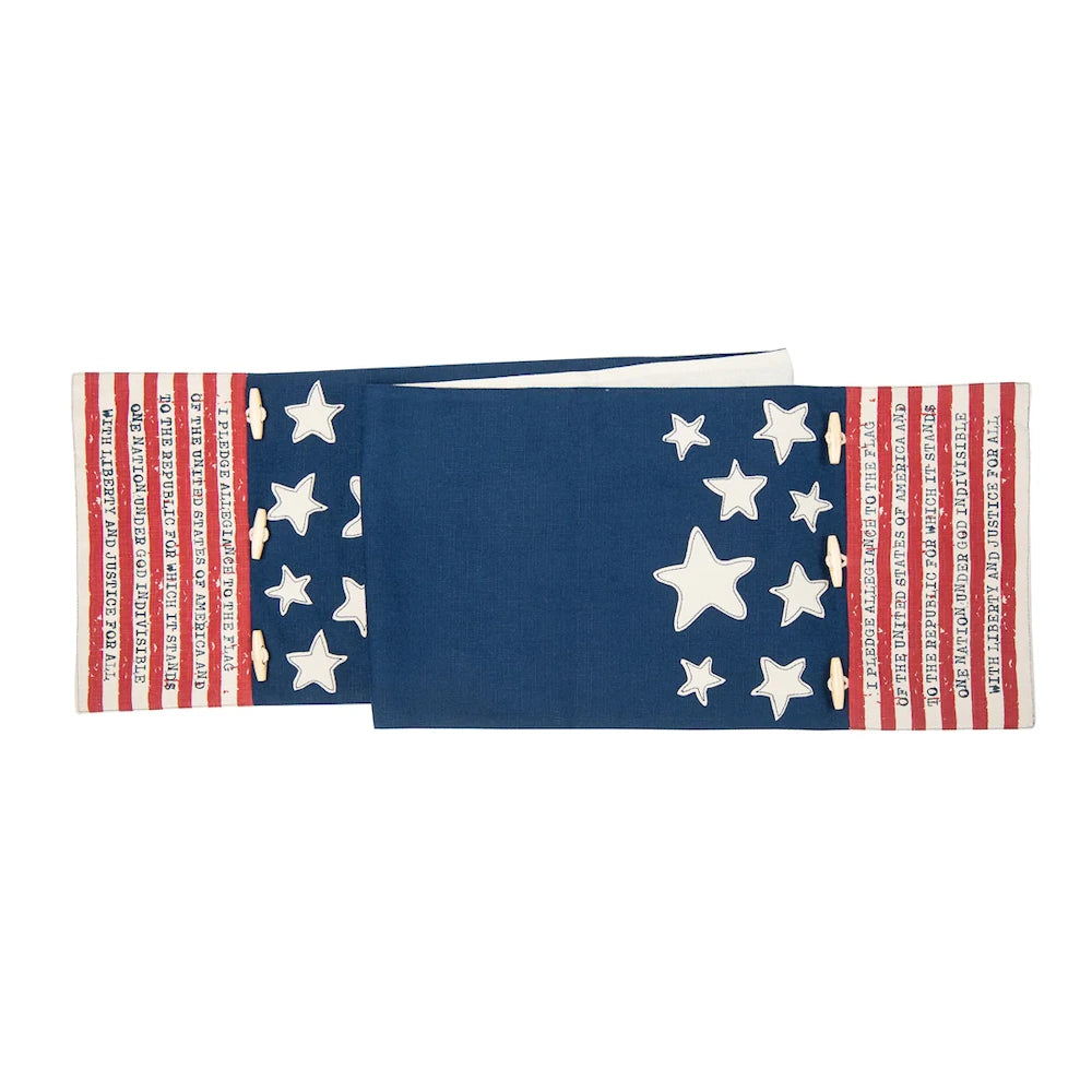 A blue and white table runner with stars and the Pledge of Allegiance printed on red and white stripes.