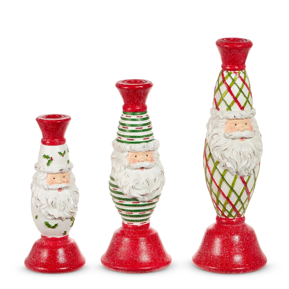 Three decorative Santa Claus candlesticks featuring different festive patterns and red bases.