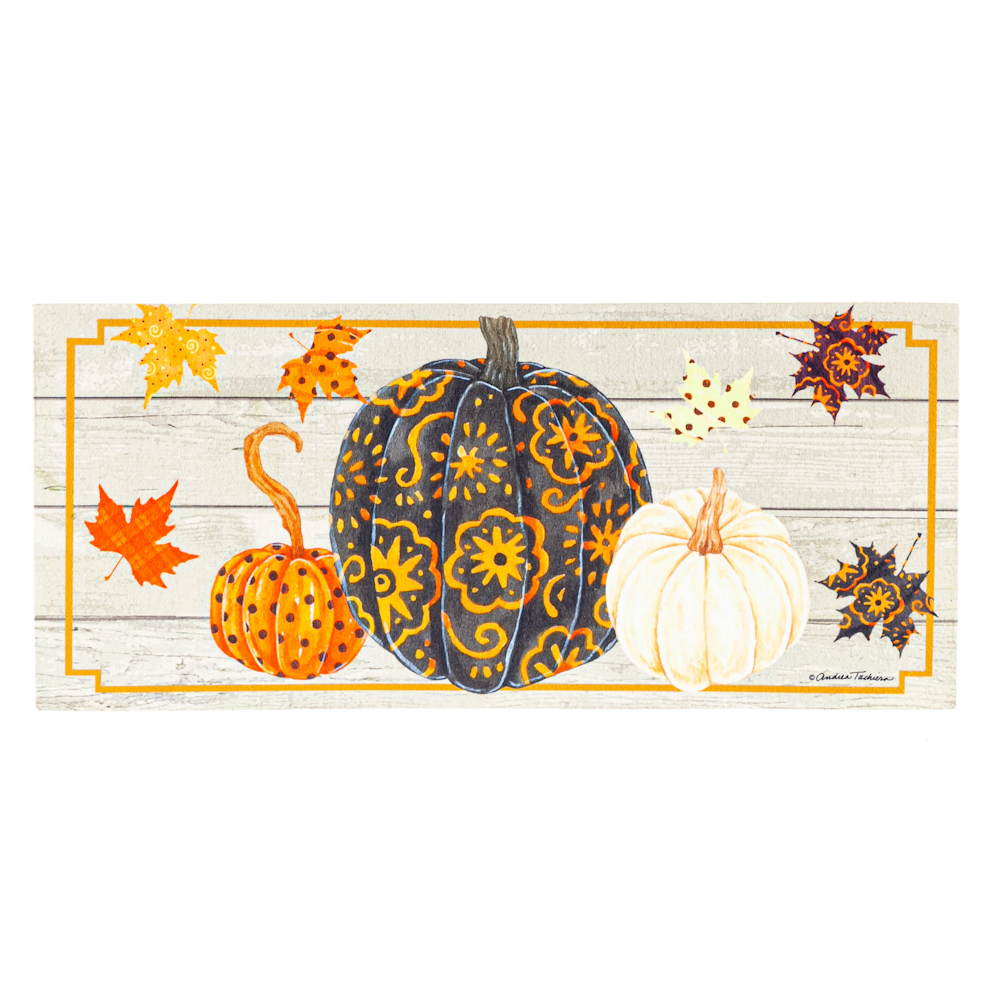 Autumn mat with patterned black, orange, and white pumpkins surrounded by colorful fall leaves.