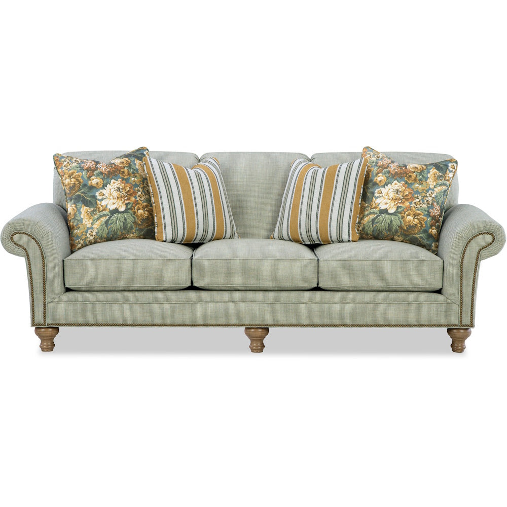 Traditional light green sofa with rolled arms, nailhead trim, wooden legs, and accent pillows.