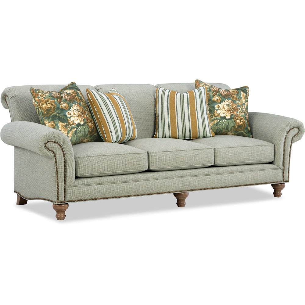Light green upholstered sofa with rolled arms, nailhead trim, turned legs, and decorative pillows.