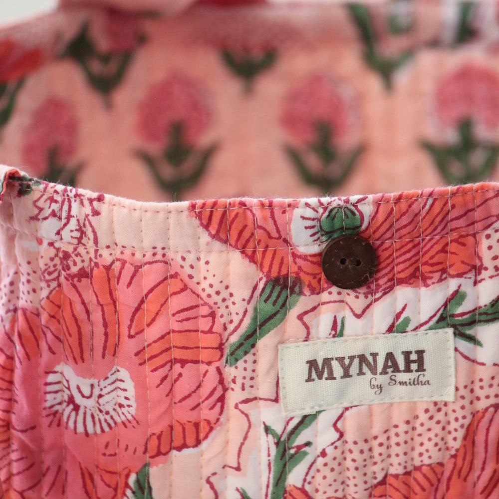 Close-up of a MYNAH by Smitha reversible quilted tote bag featuring a peach poppy floral print and a wooden button.