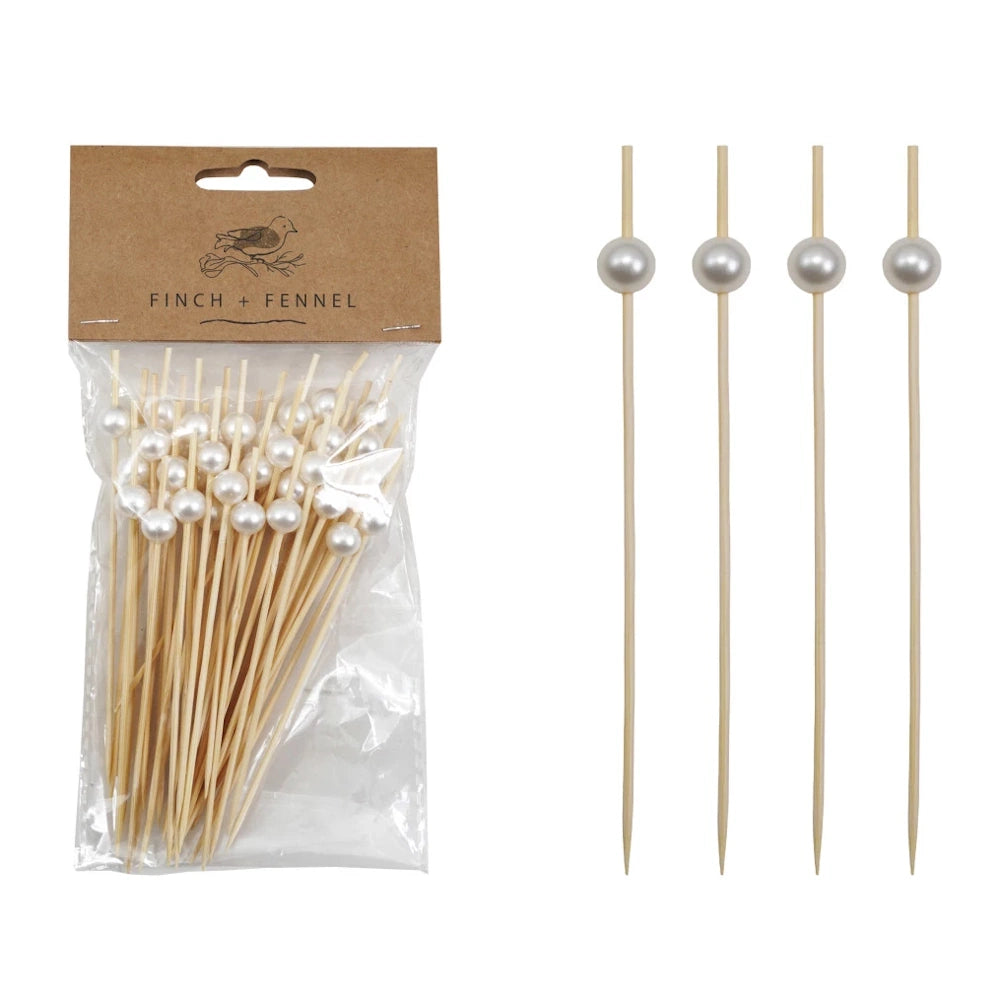 A pack of bamboo skewers with white pearl bead handles from Finch + Fennel next to four loose skewers.