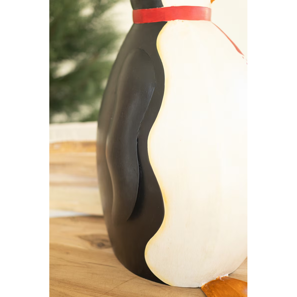 Side-view close-up of a painted metal penguin sculpture highlighting black flipper details.