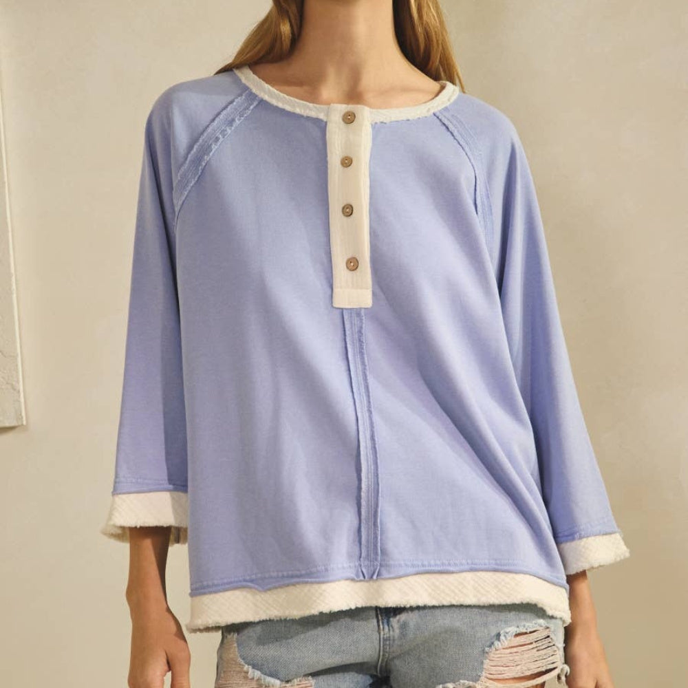 Periwinkle blue relaxed henley knit top with white trim and button details.