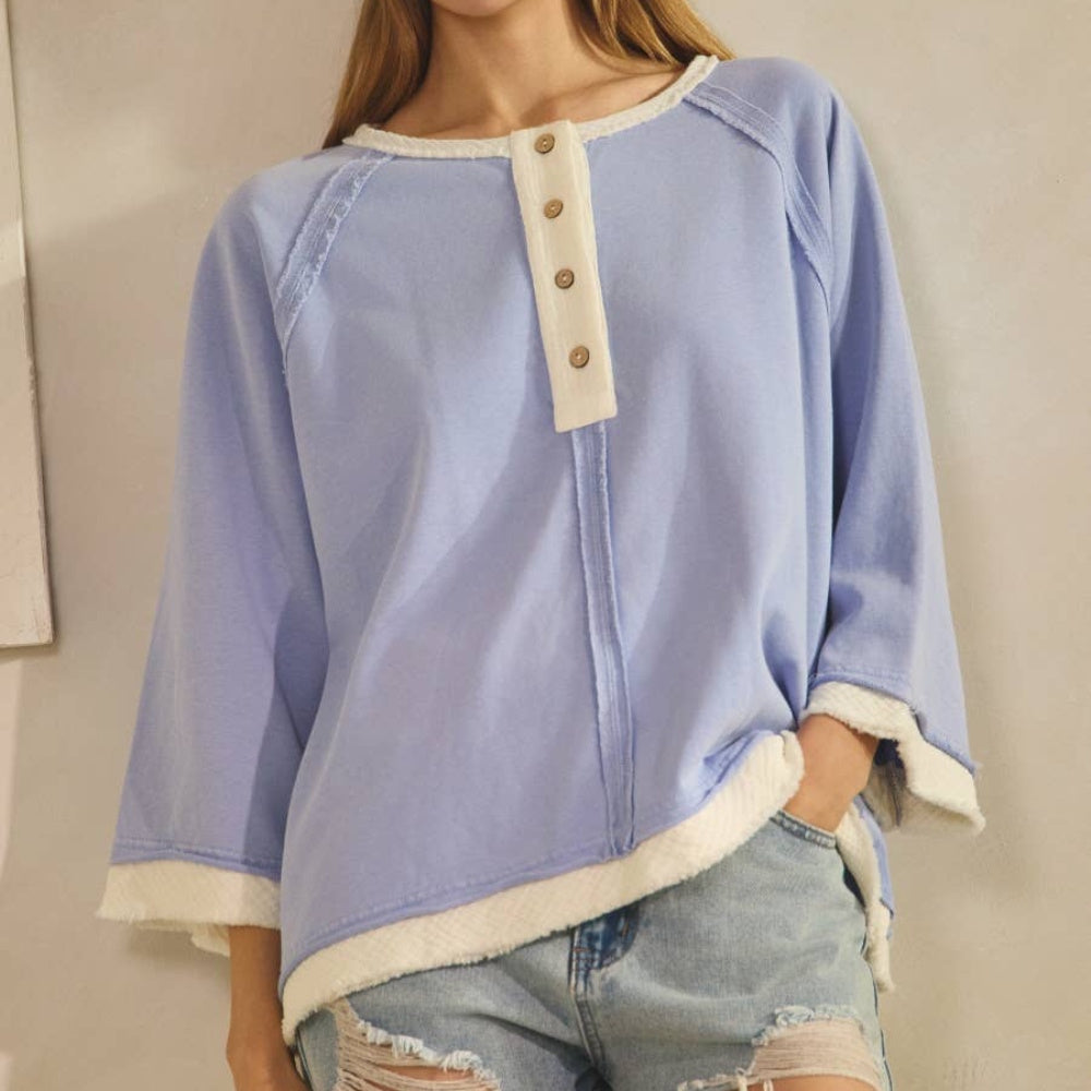 Periwinkle relaxed Henley-style knit top with cream trim and button details.