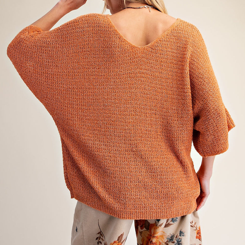 Back view of an orange textured knit V-neck sweater with loose three-quarter sleeves.
