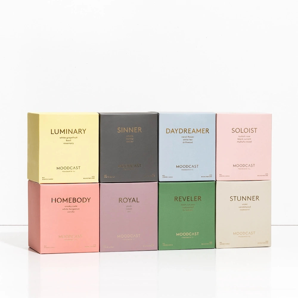 Eight pastel-colored boxed Moodcast candles arranged in two rows of four on a white surface.