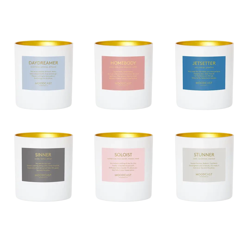 Six white candles with gold interior rims and pastel color labels arranged in two neat rows.