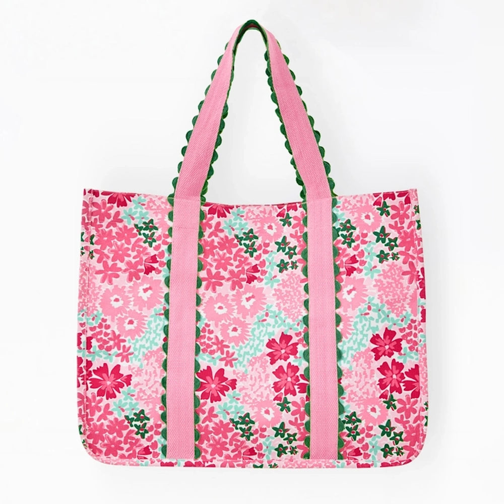 Pink floral patterned tote bag with light pink straps featuring green scalloped trim against a white background.