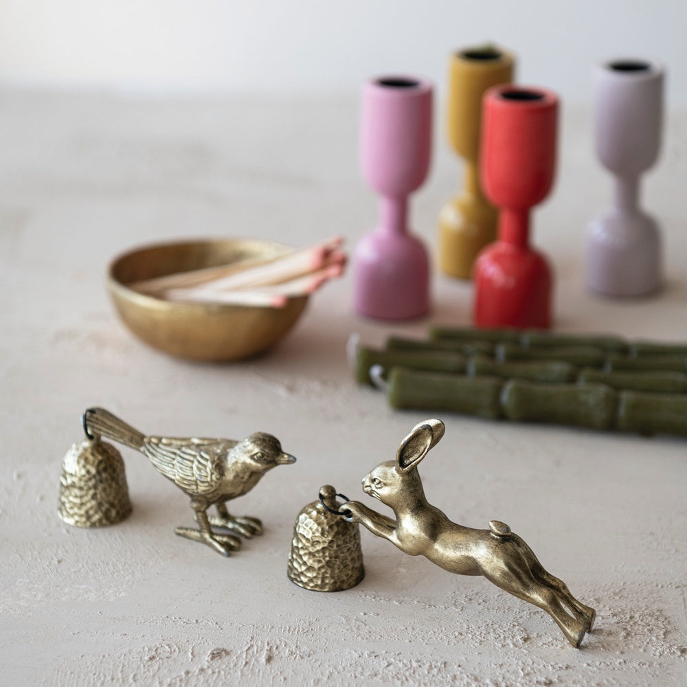 Vintage brass rabbit and bird candle snuffers with colorful candle holders and taper candles.