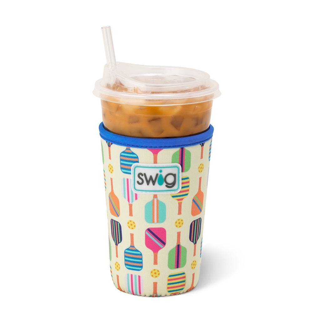 An iced coffee cup in a Swig sleeve decorated with colorful pickleball paddles and balls.