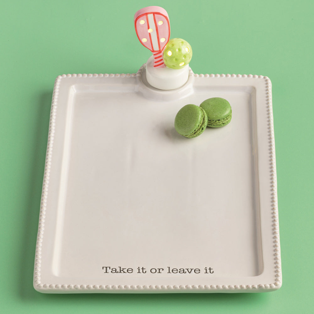 White ceramic pickleball serving tray with green macarons, "Take it or leave it" text, and a paddle and ball topper.