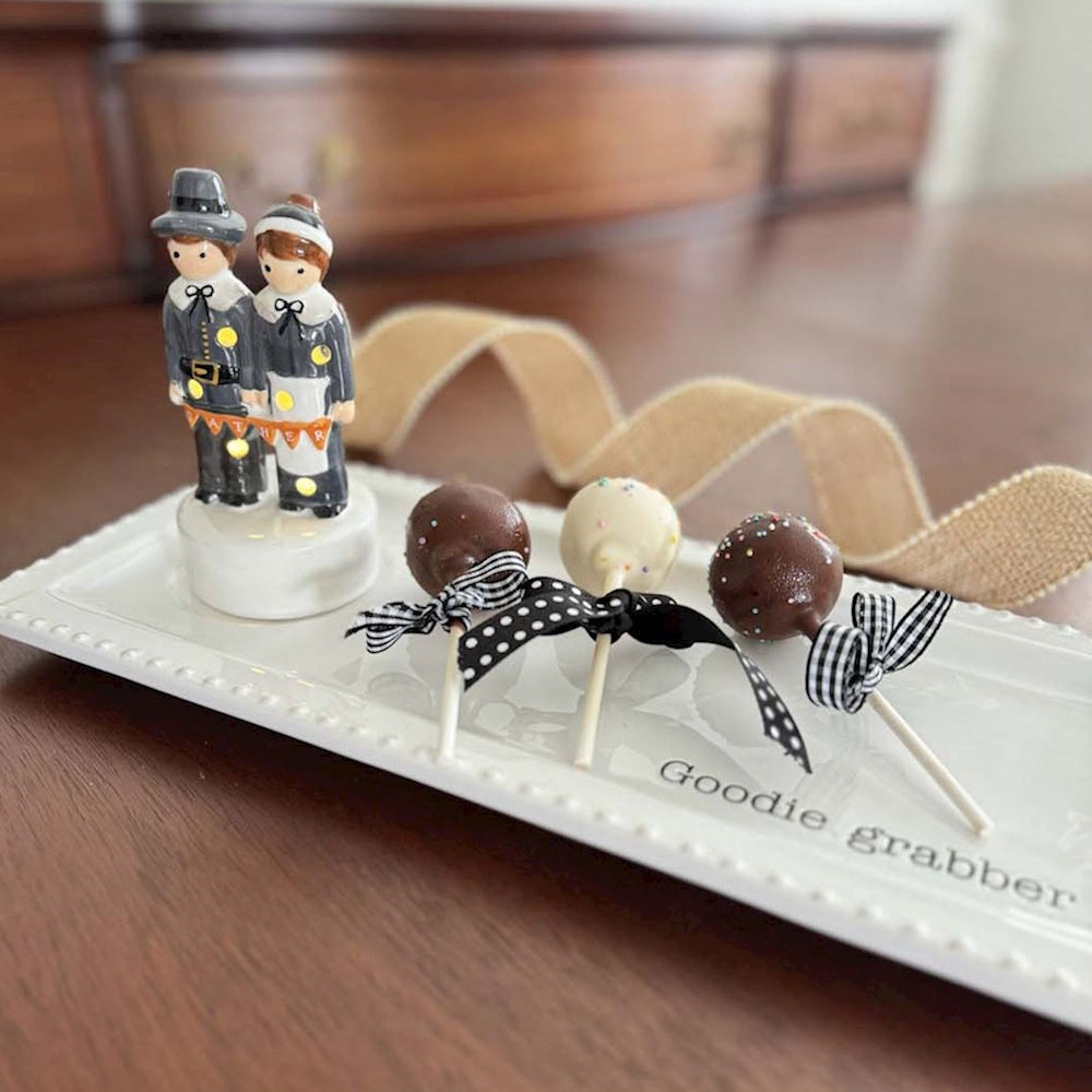 Light-up pilgrim couple figurine and cake pops on a white tray.