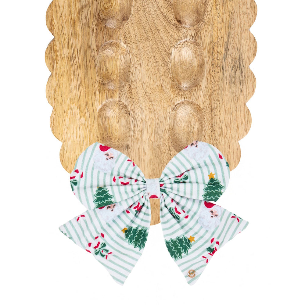 Holiday fabric bow with Santa and Christmas tree patterns attached to a wooden tray.