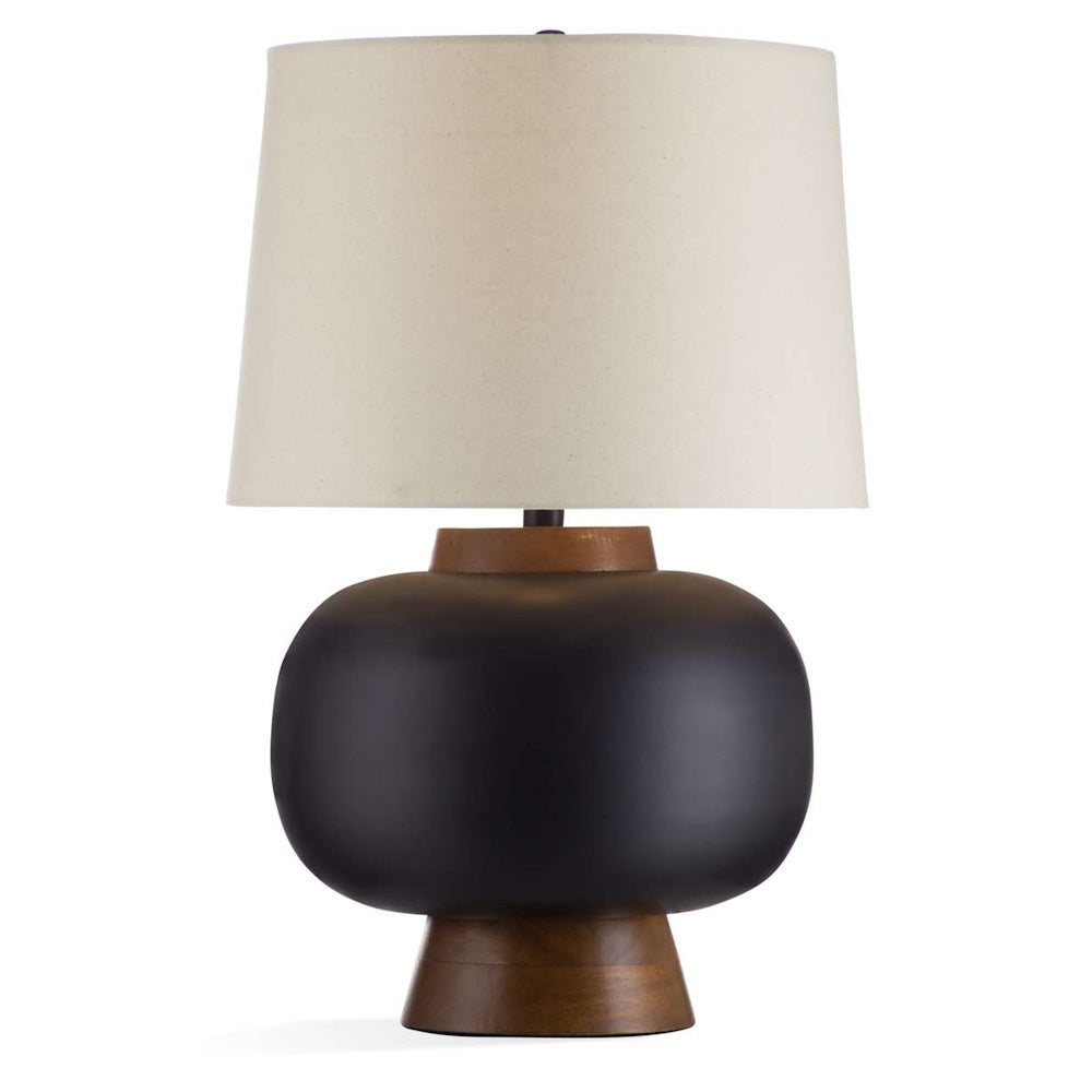 Modern matte black ceramic table lamp with walnut wood base and cream fabric drum shade on white background.