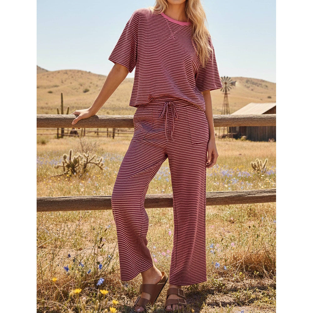 Person standing in a desert field wearing a pink and brown striped short-sleeve top and matching drawstring pants.