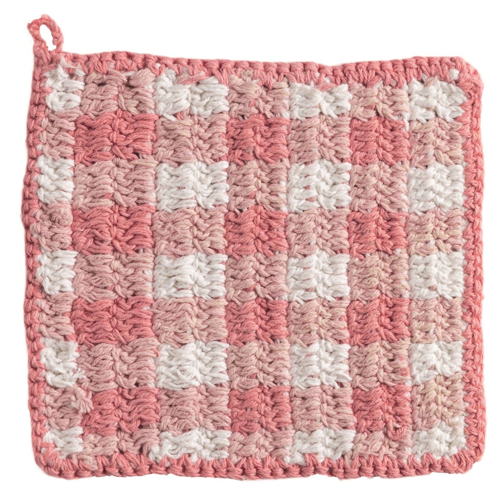 Handmade pink and white checkered crochet pot holder with a small hanging loop on a white background.