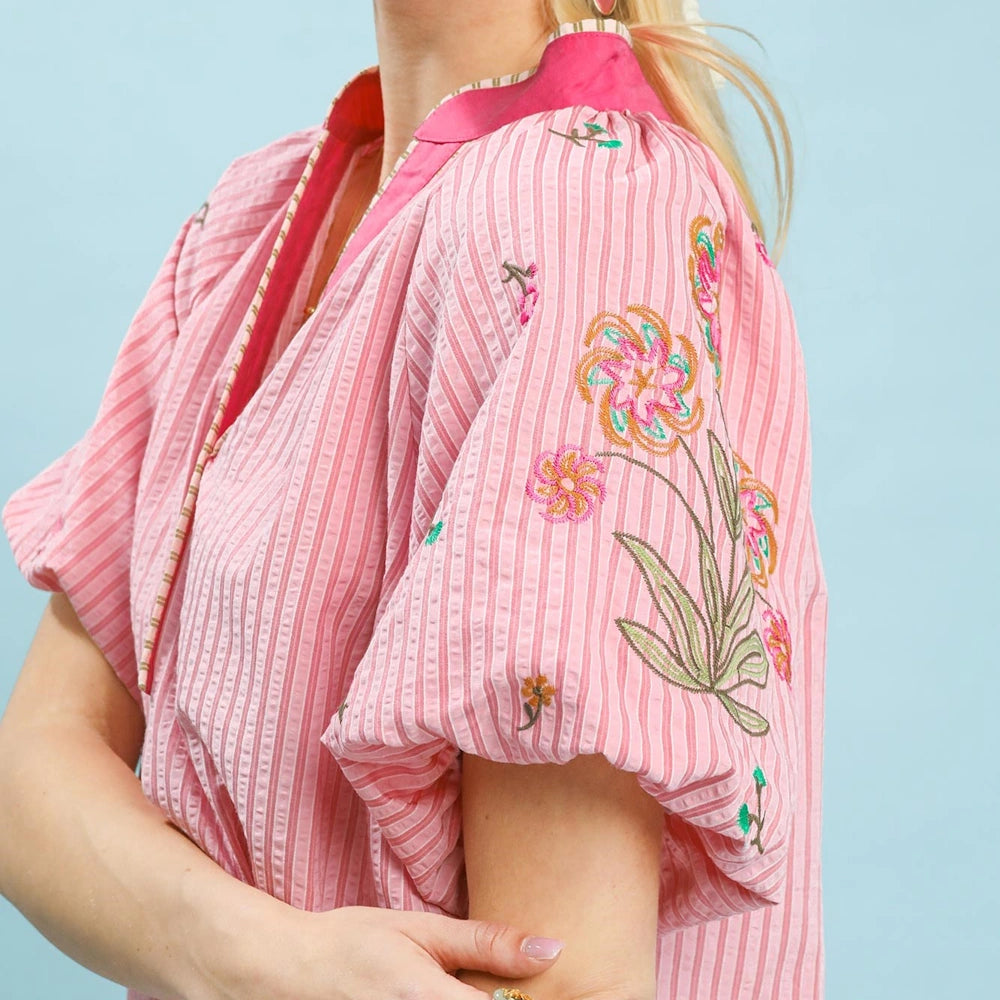 Pink striped puff-sleeve top with colorful floral embroidery on the sleeve and a bright pink mandarin collar.