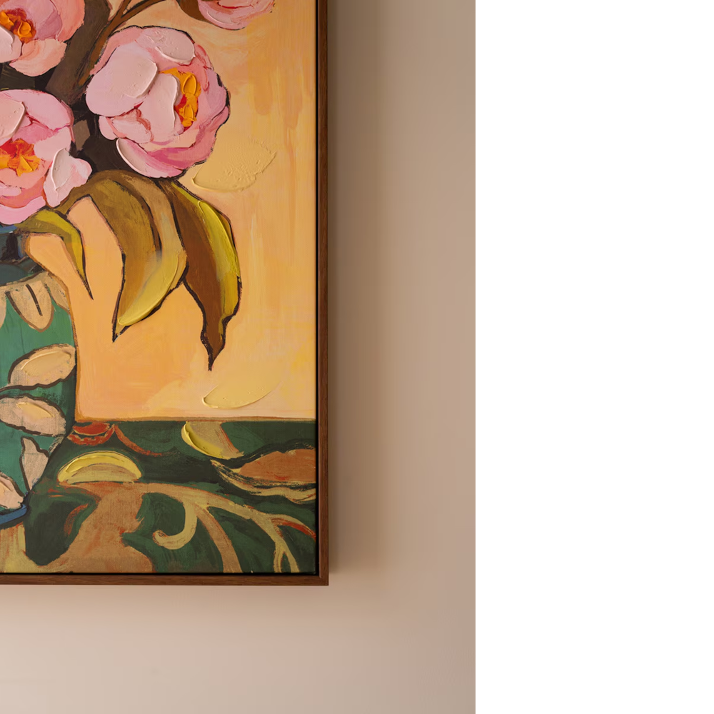Corner detail of framed floral wall art with pink peonies against a warm beige wall.