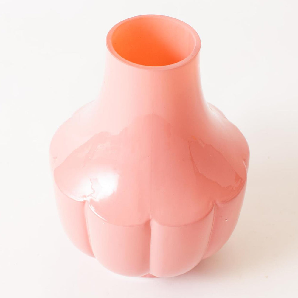 Small fluted pink glass vase with a glossy finish and scalloped base on a white background for home decor.