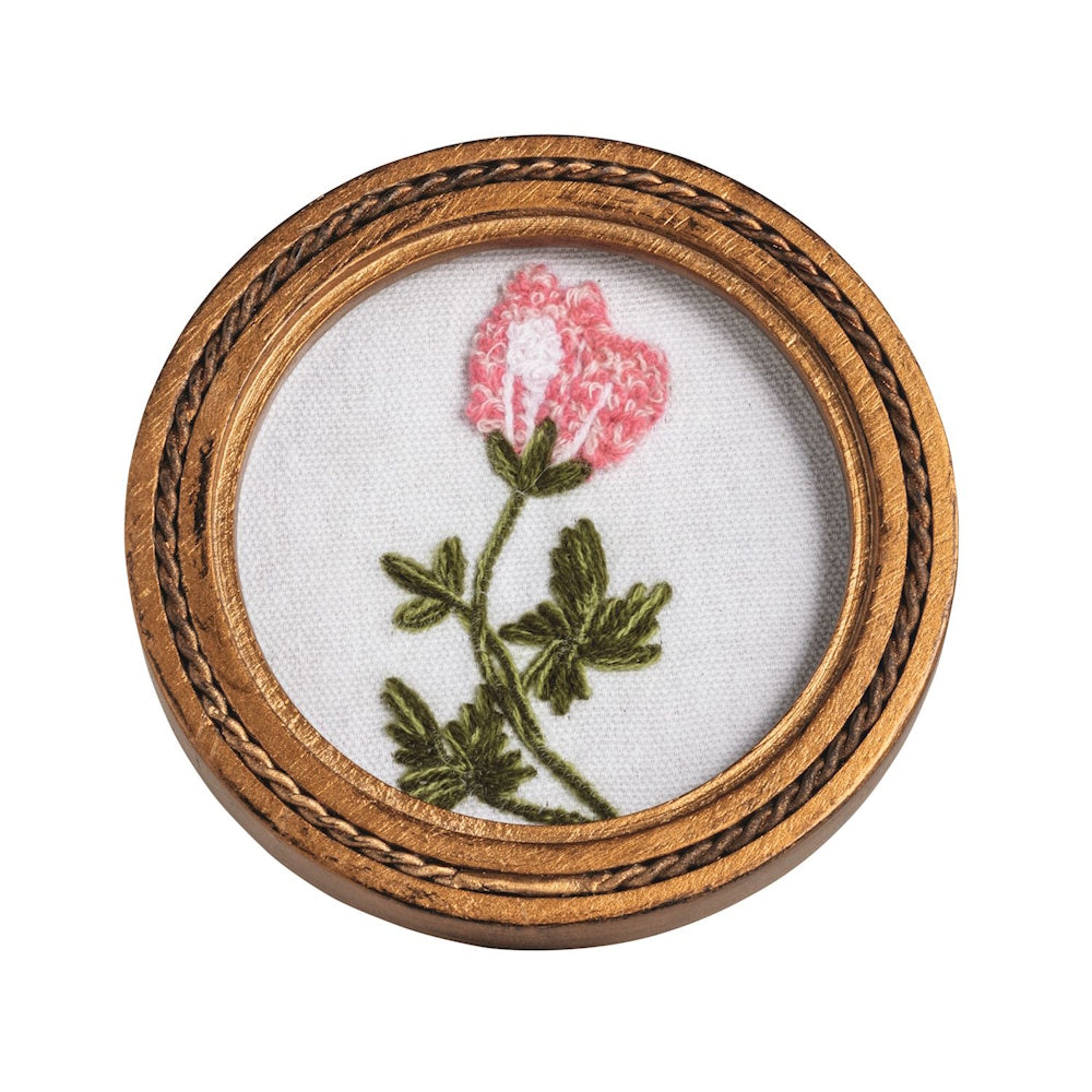 Hand-embroidered pink flower with green leaves in a round gold frame, isolated on a white background for wall decor.