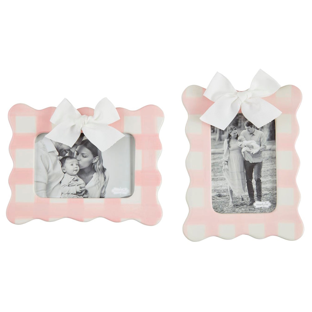 Two pink gingham ceramic photo frames with scalloped edges and white bows, featuring family photos.