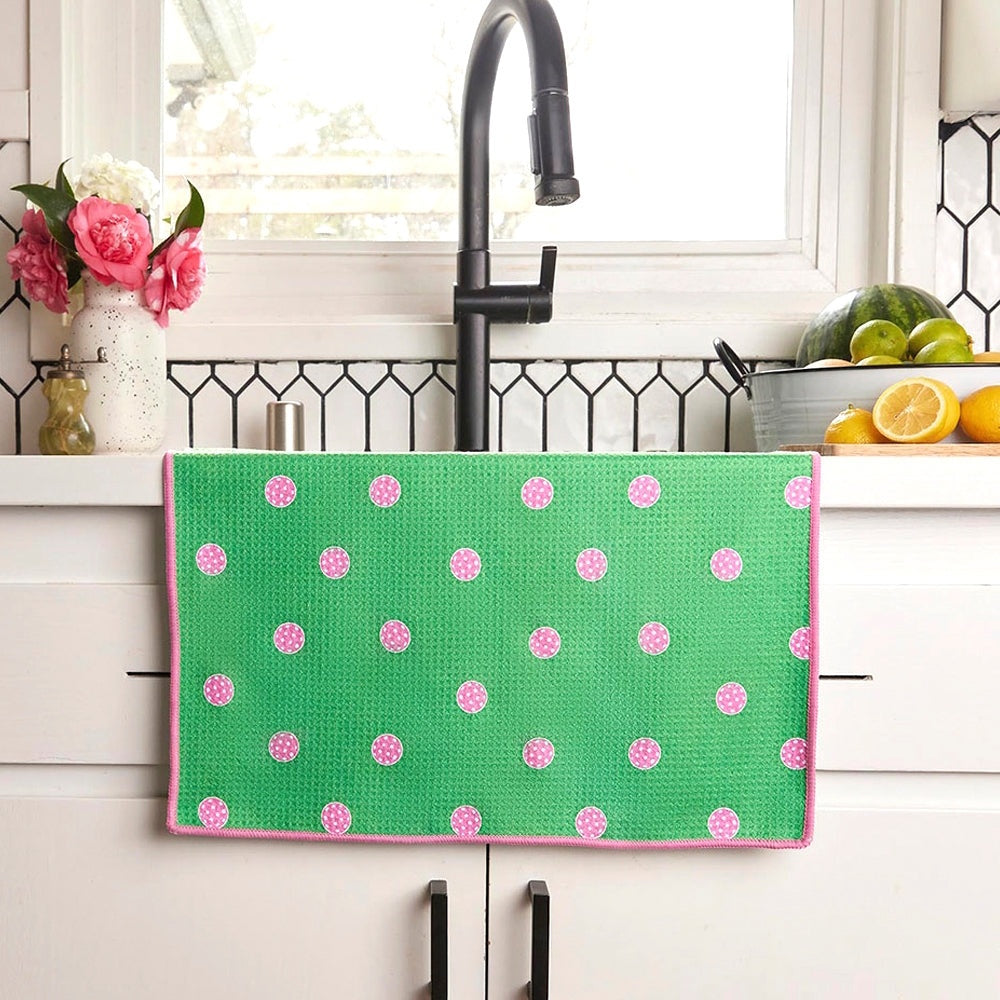 Green waffle knit tea towel with pink pickleball polka dots hanging in a kitchen.