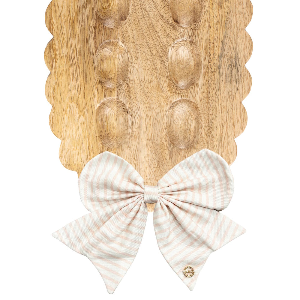 Pink and white striped fabric bow on a scalloped wooden egg tray.