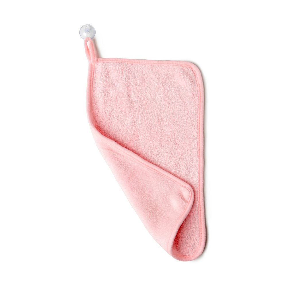 Pink microfiber makeup removing towel hanging on a suction cup hook, isolated on white background.