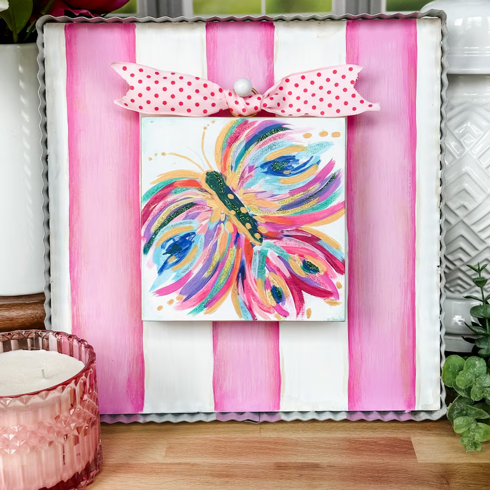 Colorful butterfly art on a pink and white striped display board with a polka dot bow and corrugated metal trim.