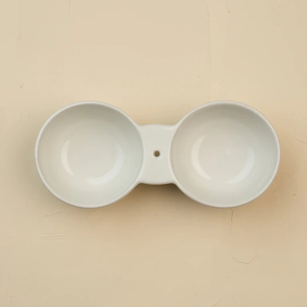 Top-down view of a white ceramic double dipping bowl with a small hole in the center bridge.