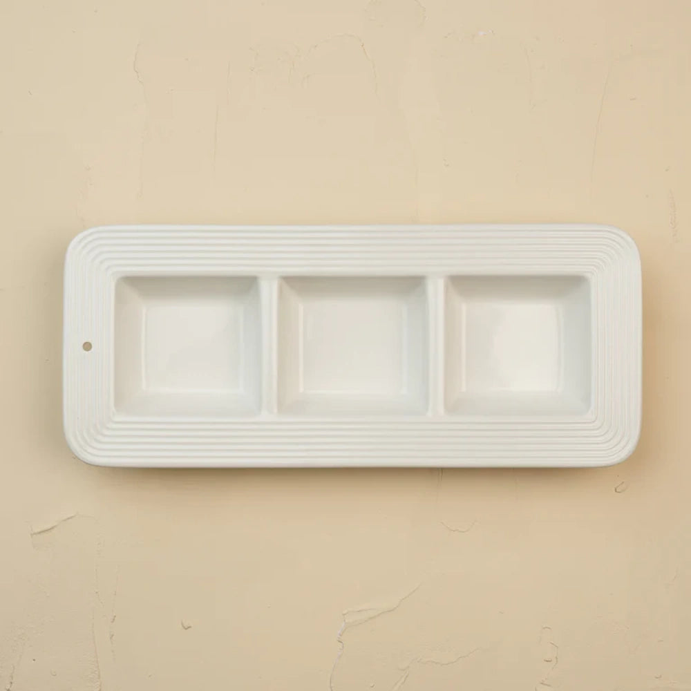 Three-compartment white ceramic dish with a textured pinstripe rim and a small hole on the left side.