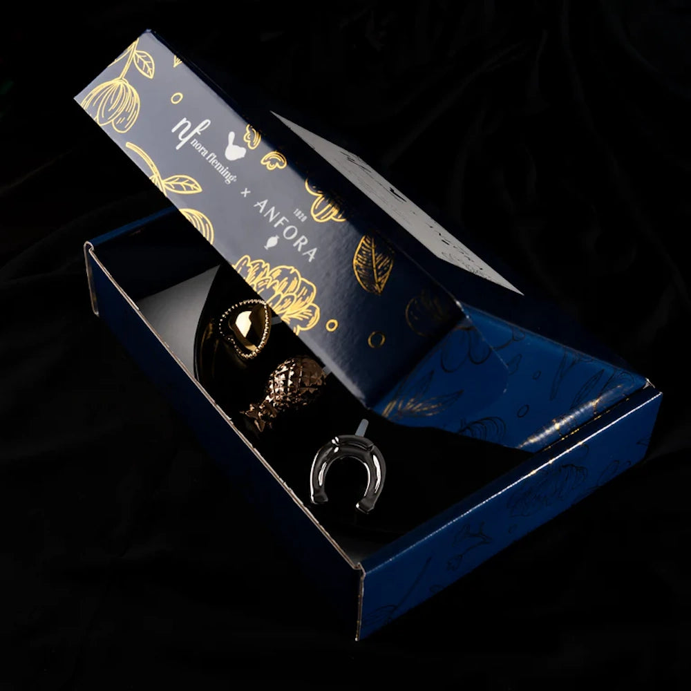 An open blue and gold gift box displaying decorative mini charms against a black background.