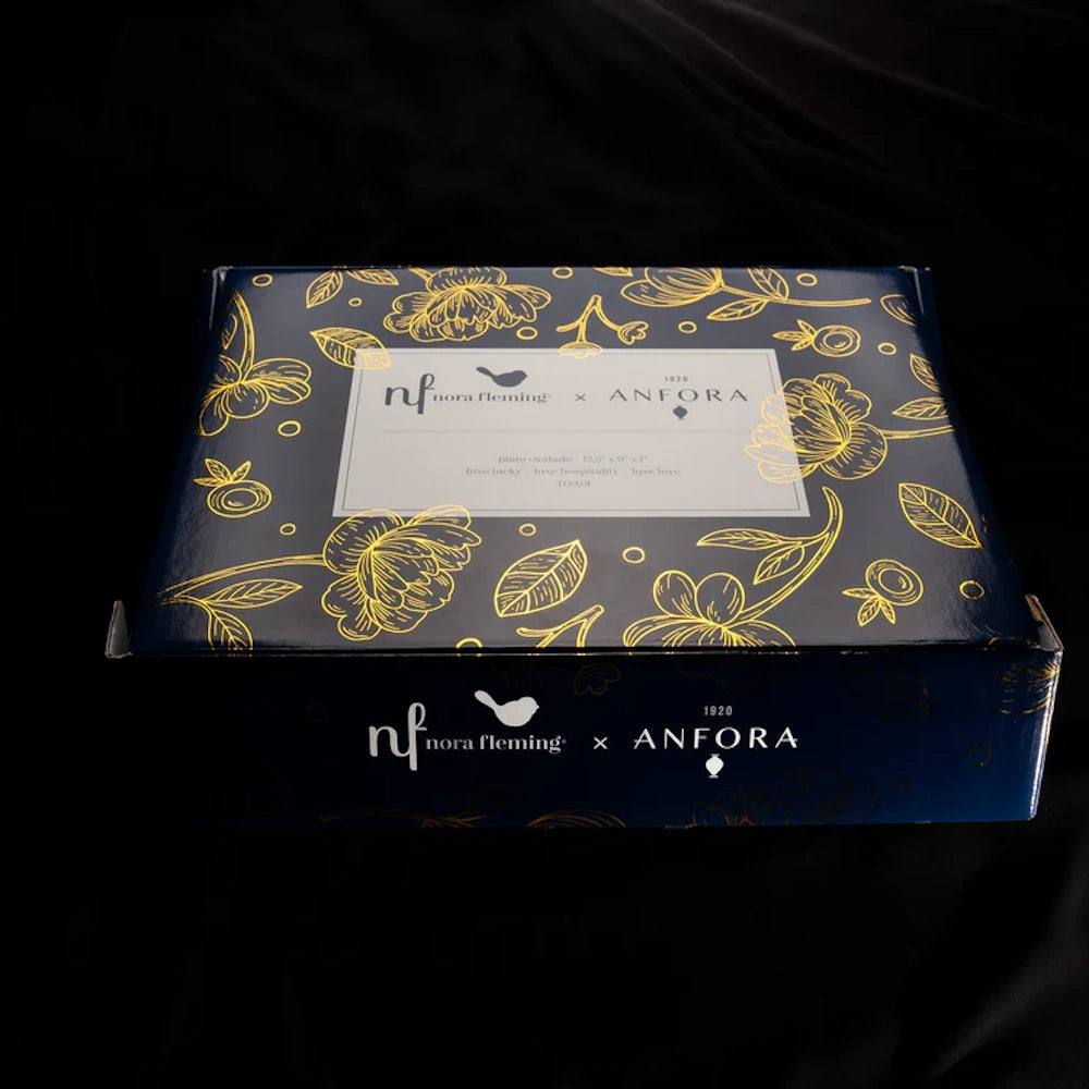 Dark navy gift box featuring gold floral illustrations and Nora Fleming x Anfora branding on top.