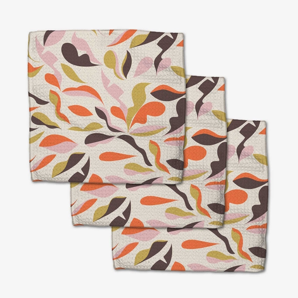 A set of three square dishcloths featuring an abstract, colorful pattern of orange, pink, and olive leaves.
