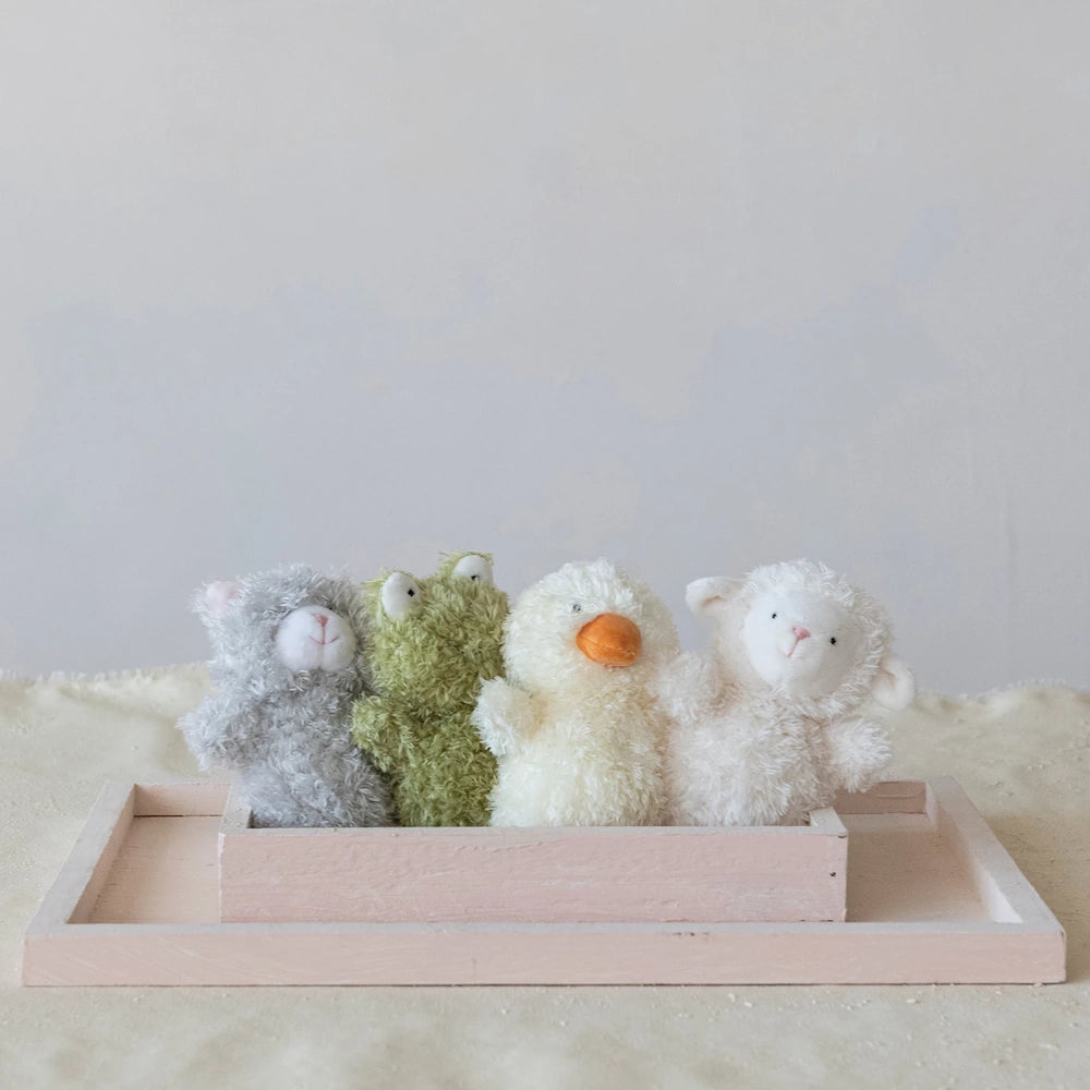Four fuzzy plush animal toys, cat, frog, duck, and lamb, sitting in a pink wooden tray for children's nursery decor.