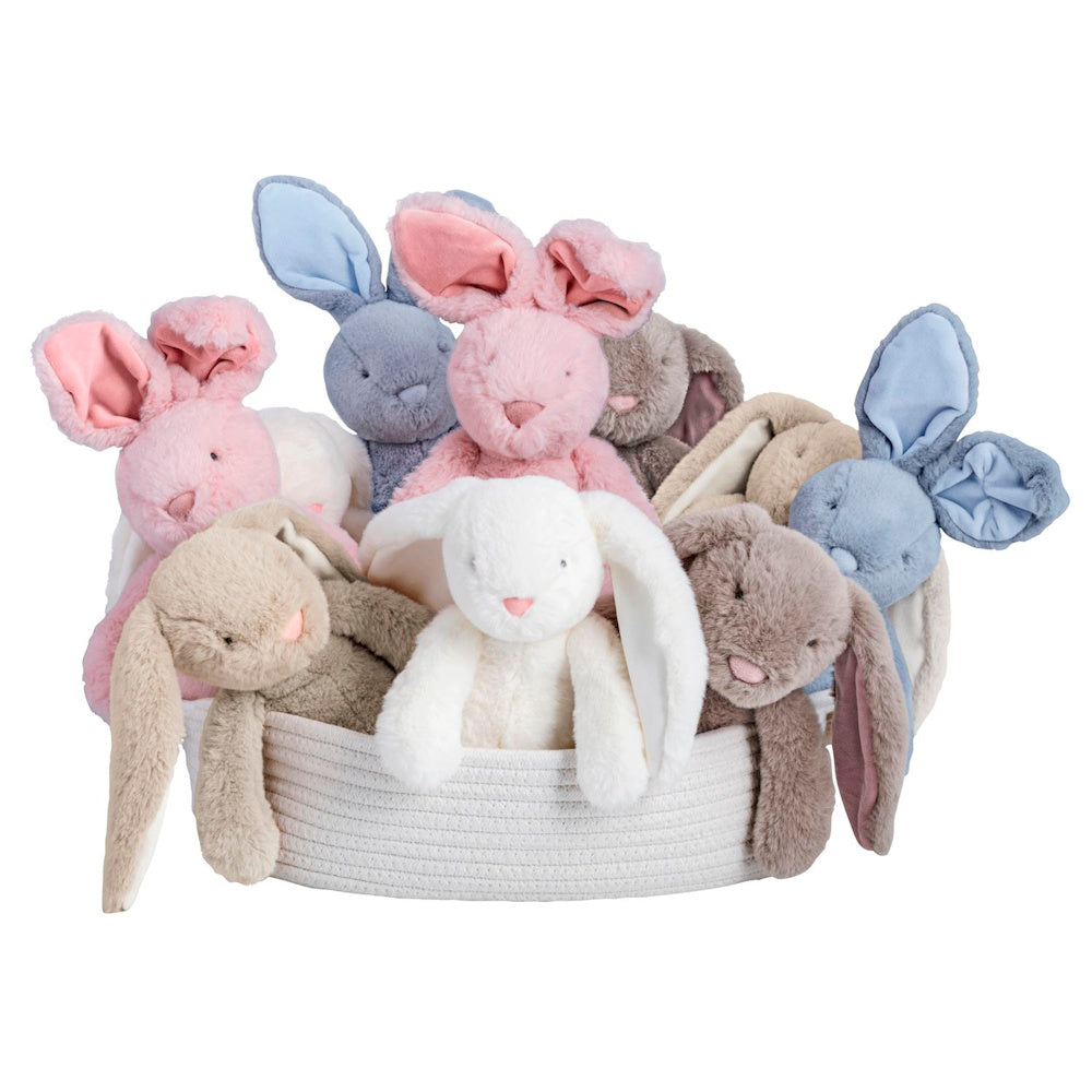 Assorted plush bunny rabbits in pink, blue, white, and tan sitting in a woven basket on a white background.
