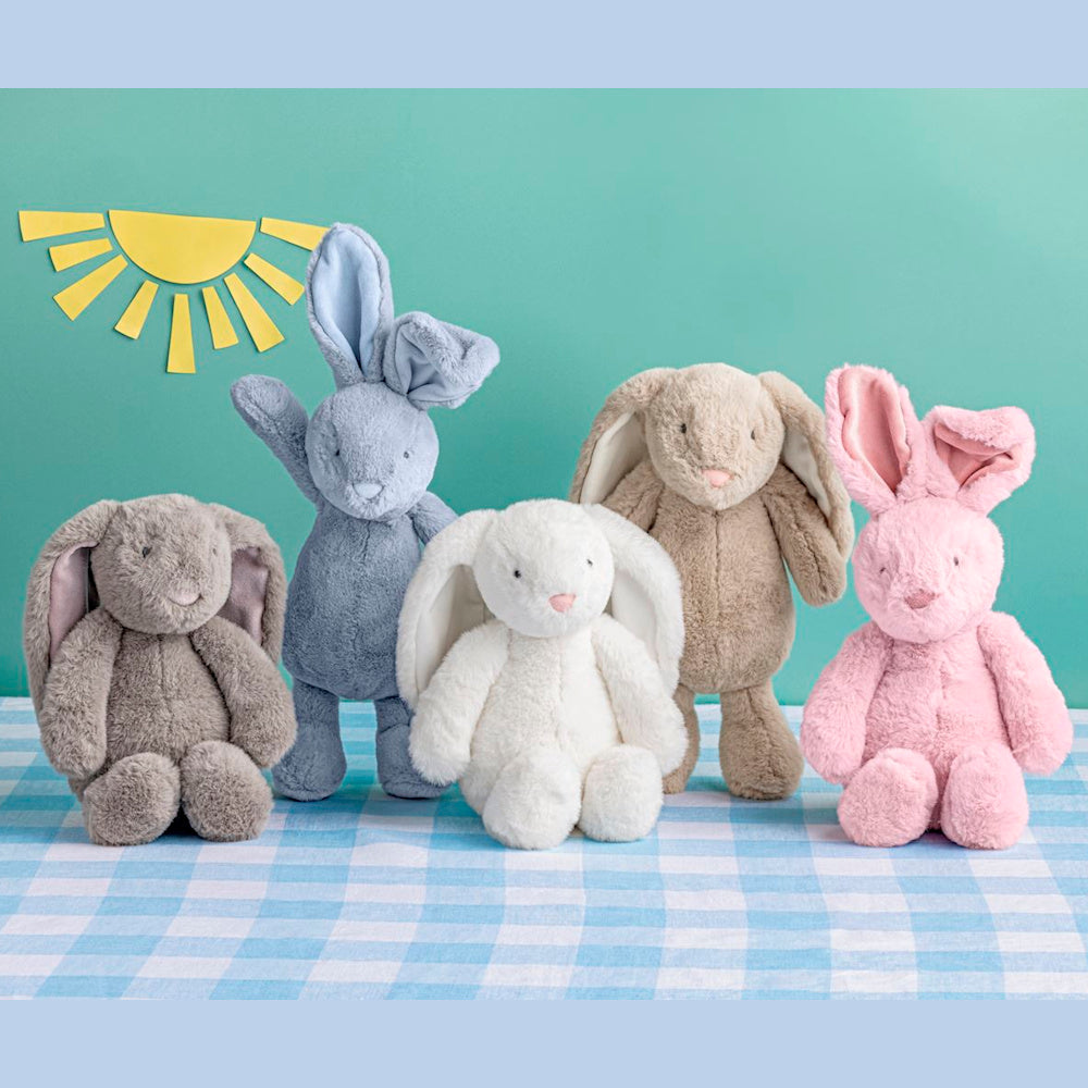 Five plush bunny toys in grey, blue, white, tan, and pink arranged on a blue checkered surface against a teal background.