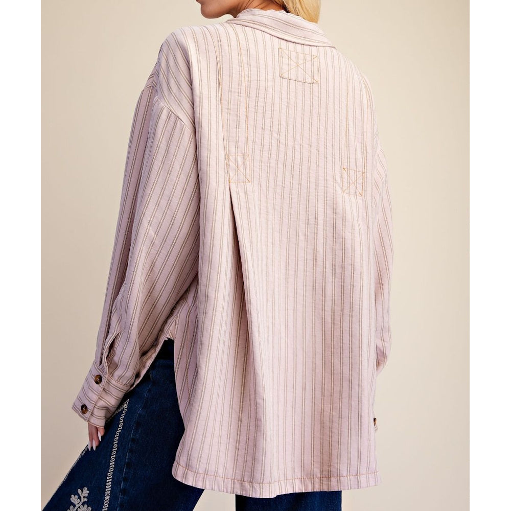 Back view of a woman wearing an oversized striped button-down shirt with box pleats and side vents.
