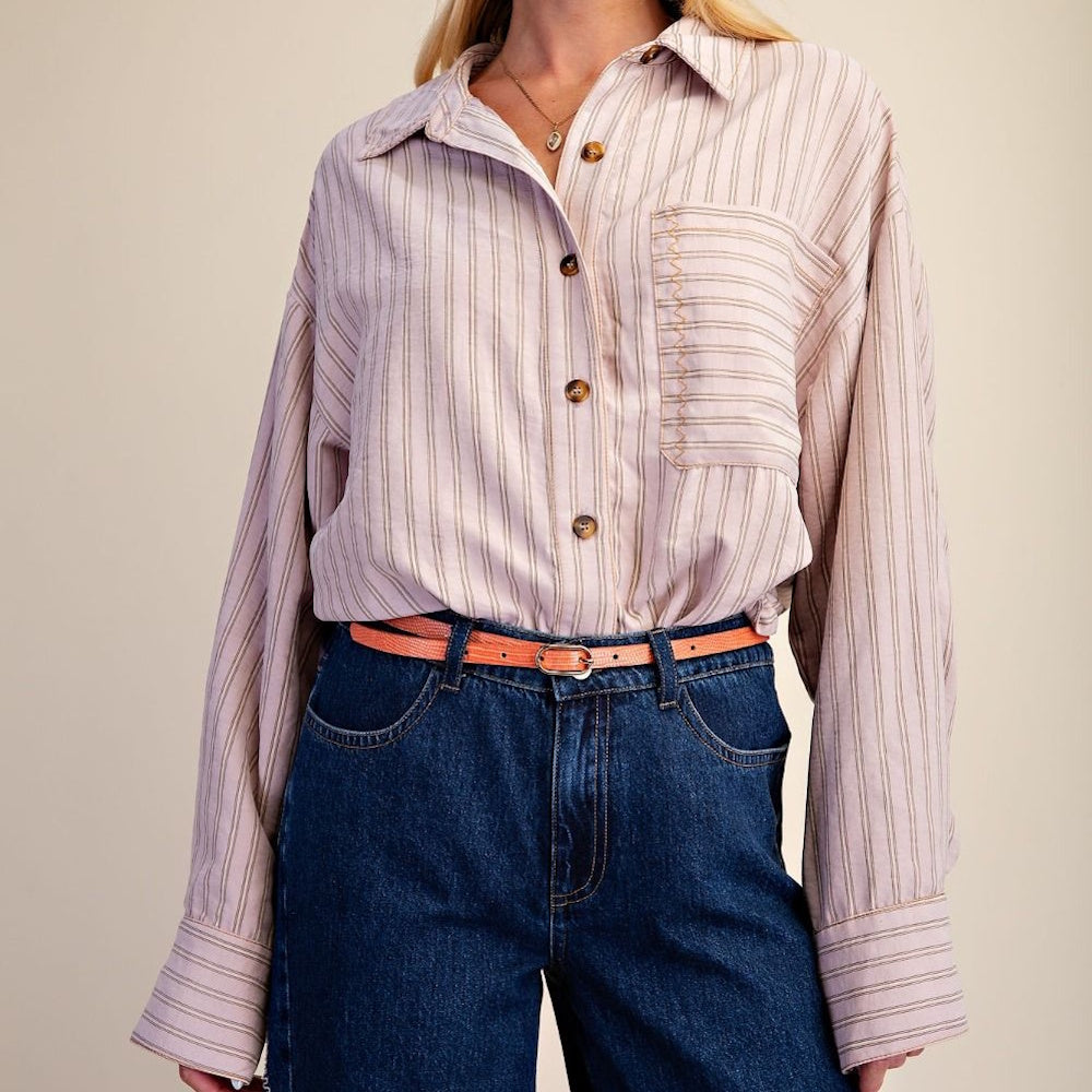 Woman in a striped button-down shirt tucked into jeans with an orange belt.