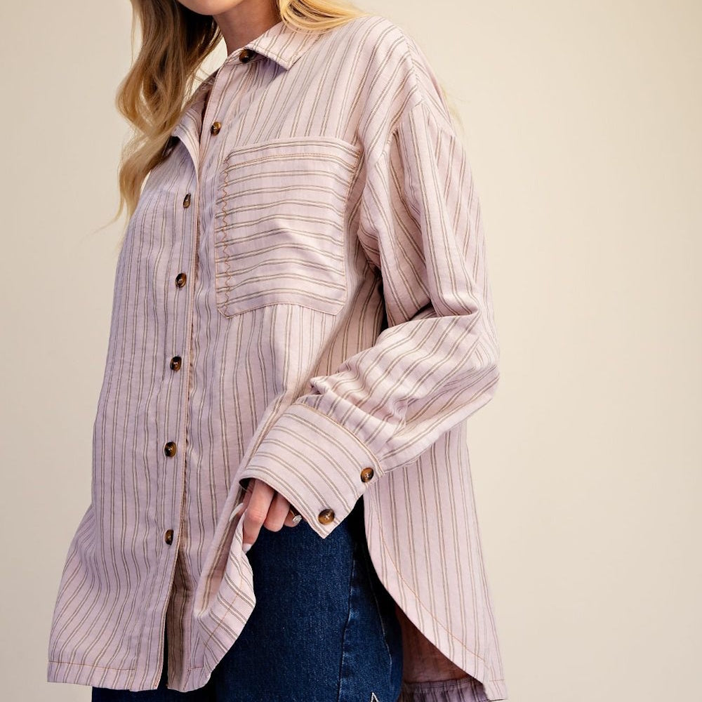 Side profile of a woman wearing an oversized striped button-down shirt with high side slits.