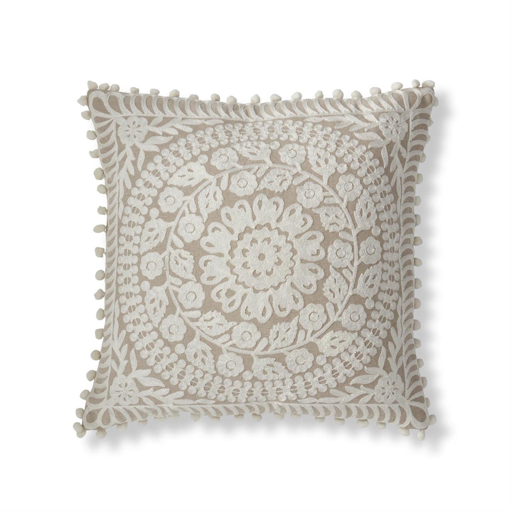 Beige boho pillow featuring cream floral embroidery, a circular mandala design, and decorative pom-pom trim.