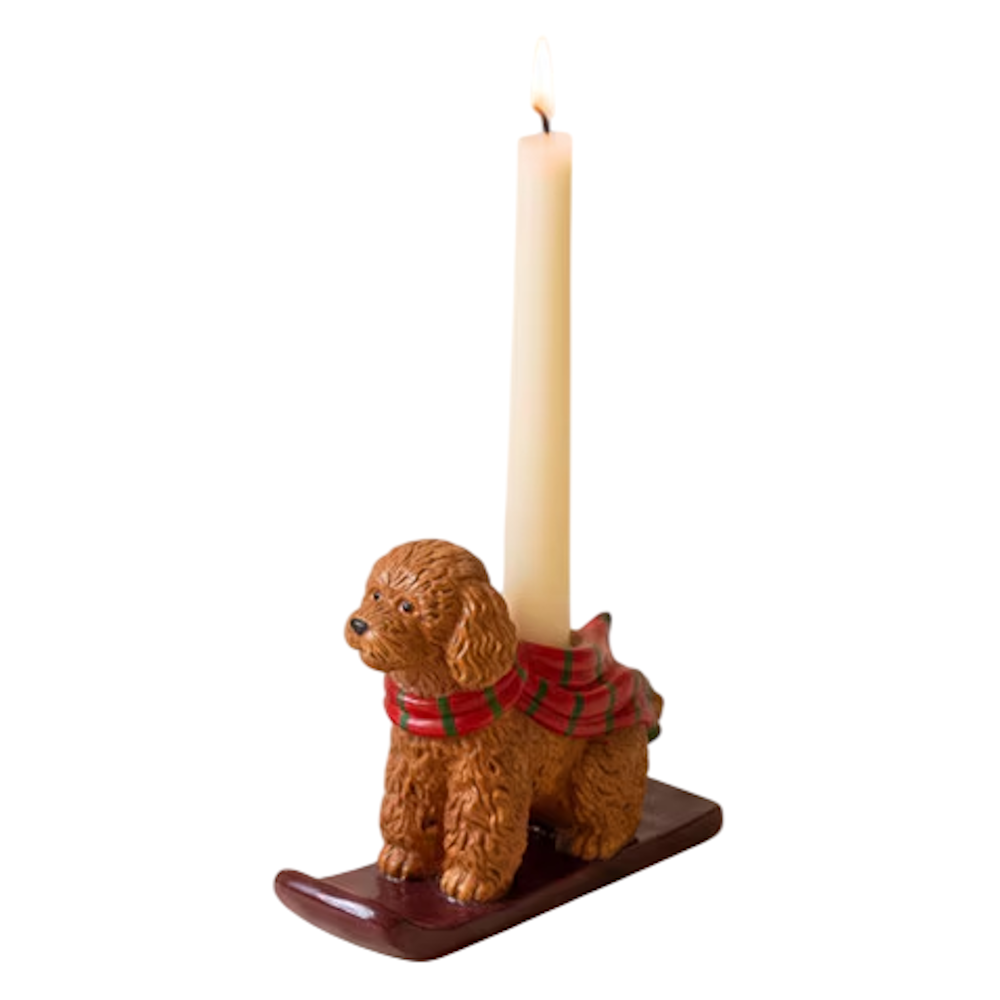 Ceramic brown poodle taper candleholder wearing a red and green scarf on a dark sled.
