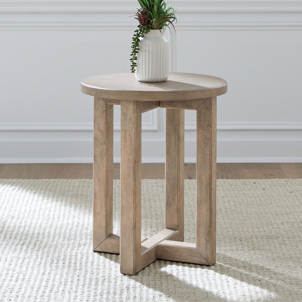 Round Proximity Place wooden chairside table with a vase on top in a living room.